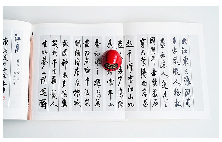 日製鐵達摩擺件，南山居紅色達摩禪意擺件，圓潤飽滿，靜置於古籍書法之上，彰顯茶室雅趣。