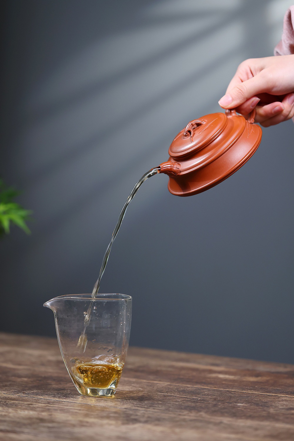 宜興紫砂壺原礦朱泥竹影周盤壺(190ml)，南山居手工朱泥扁壺，壺身溫潤圓融，壺蓋竹節鈕精緻，出水流暢，將金黃茶湯注入晶透玻璃公道杯。