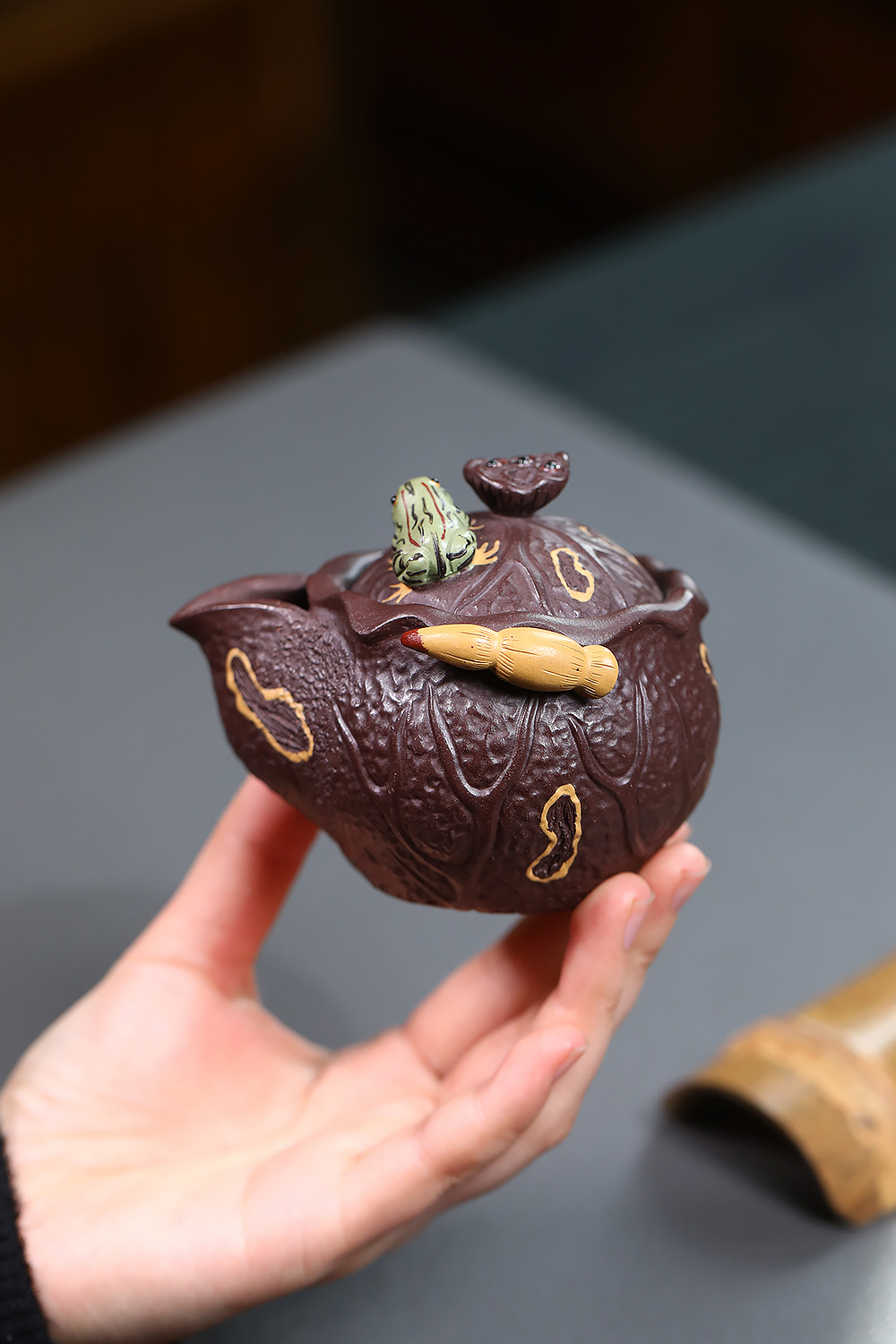 宜興紫砂壺原礦紫泥荷塘月色仿生手抓壺(150ml)，南山居手工紫砂茶壺，壺身暗紅質感，蓋鈕飾有生動青蛙與荷葉，壺側浮雕竹筍，獨具禪意。
