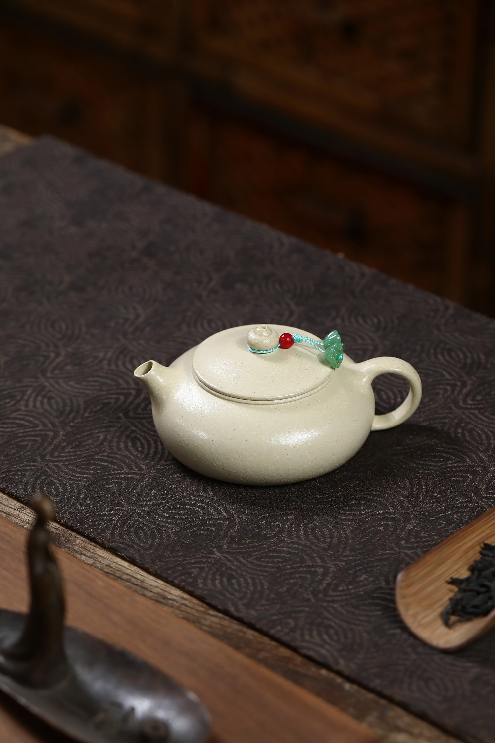 宜興紫砂壺原礦本山綠泥寒江月壺(150ml)，南山居段泥扁腹壺，壺身呈現古樸溫潤光澤，搭配精緻壺繩與玉石吊墜，展現禪意茶道之美。