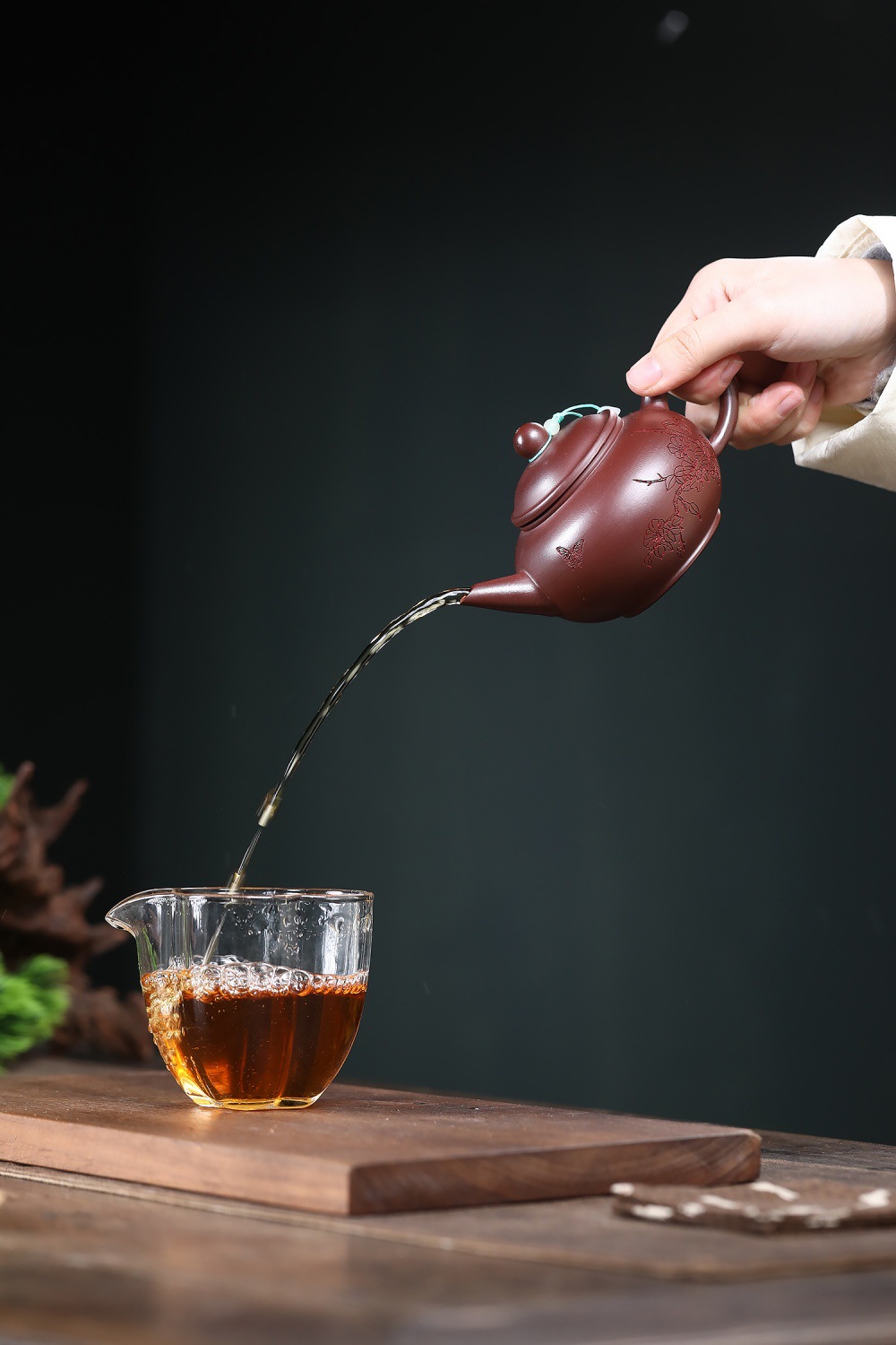 宜興紫砂壺原礦紅泥蝶戀花水平壺(210ml),南山居手工紫砂茶壺傾茶入玻璃公道杯,壺身雕花精緻,茶湯琥珀溫潤。