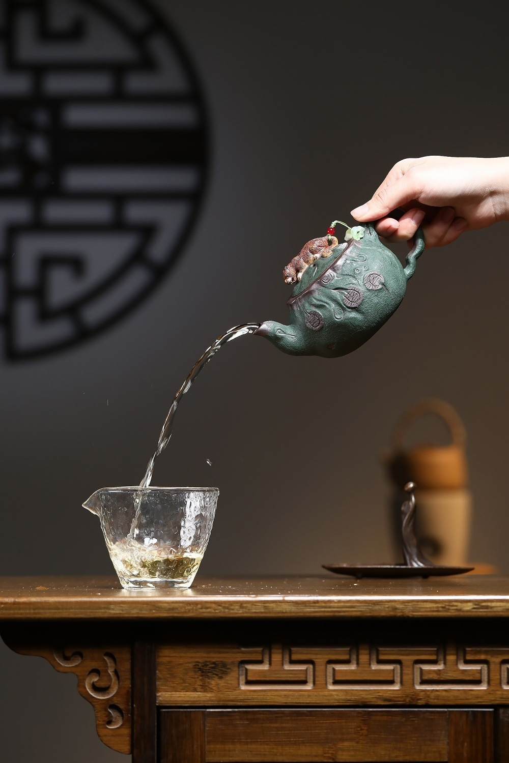 宜興紫砂壺原礦紫泥金錢豹仿生壺(310ml)，南山居手工綠泥紫砂壺，壺身雕刻精緻，茶水傾注於玻璃公道杯中，展現流暢出水美感。