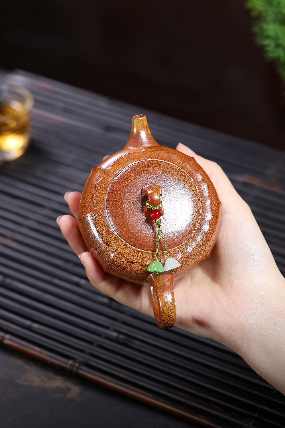 宜興紫砂壺原礦龍骨金砂荷氣生財壺(180ml)，南山居手工紫砂圓壺，壺身雕刻蓮瓣紋飾，提把配飾玉珠流蘇，展現精緻茶道。