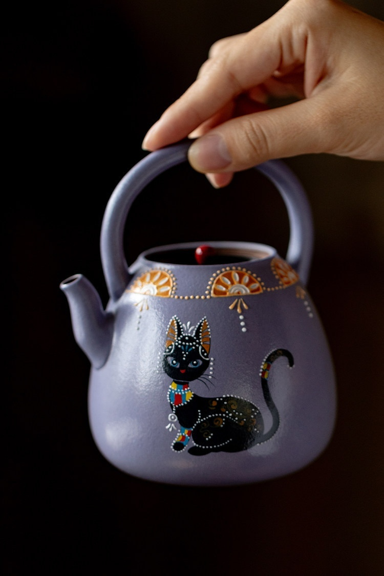 紫苑星芒喵影 - 入夢提梁茶壺，南山居手繪紫砂提樑壺，薰衣草紫壺身融合精緻貓咪彩繪，兼具傳統工藝與現代童趣藝術。