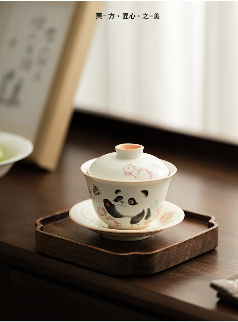 定窯熊貓戲蝶三才蓋碗，南山居熊貓彩繪手作蓋碗，釉色溫潤细腻，繪有靈動可愛的熊貓與繁花圖案，呈現東方美學與茶藝之趣。