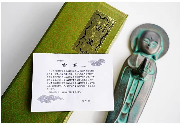 日本高岡地藏王菩薩佛珠掛台擺件，圖片顯示一尊帶有綠色鏽蝕的禪意銅像，搭配日式包裝盒與說明卡，為南山居茶席增添雅致。