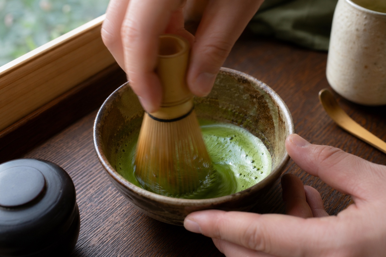 使用茶筅以 W 字型手勢刷抹茶，形成細緻泡沫